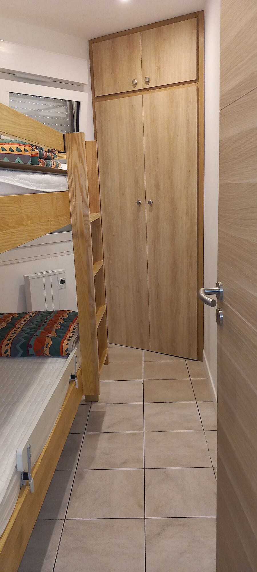 Enclosed cabin bedroom with bunk beds, window and wardrobe