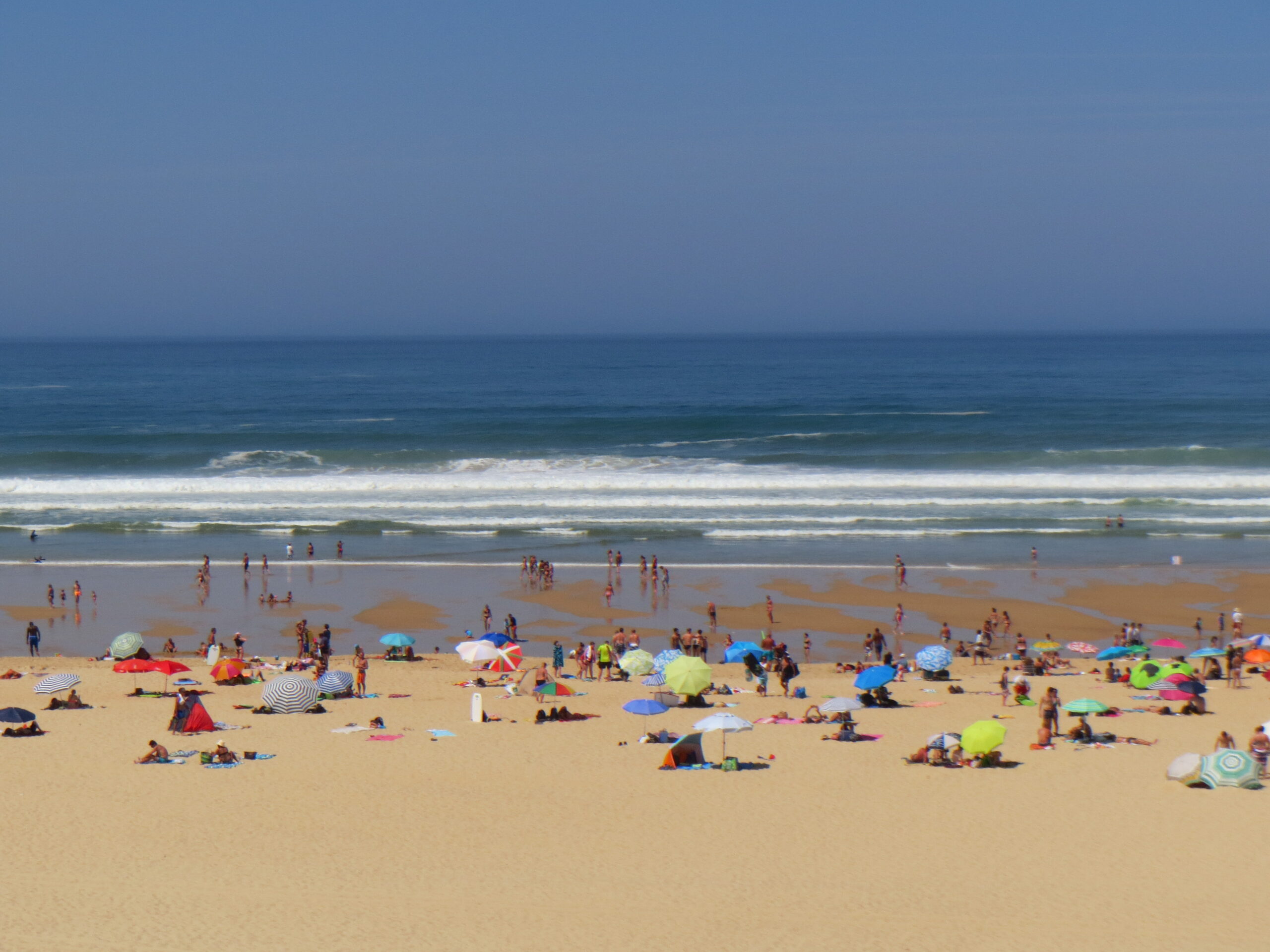 Colourful parasols on Moliets beach with Atlantic waves behind